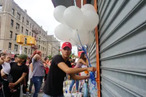 Justice for Junior - A brother of Lesandro "Junior" Guzman-Feliz ties balloons to the gates of the deli where his brother was killed